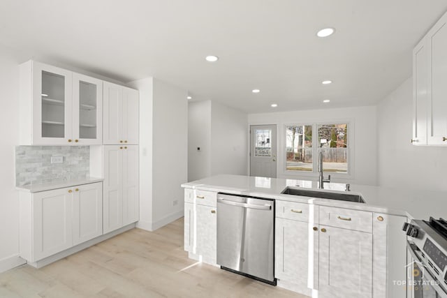 kitchen with decorative backsplash, appliances with stainless steel finishes, light wood-type flooring, sink, and white cabinets