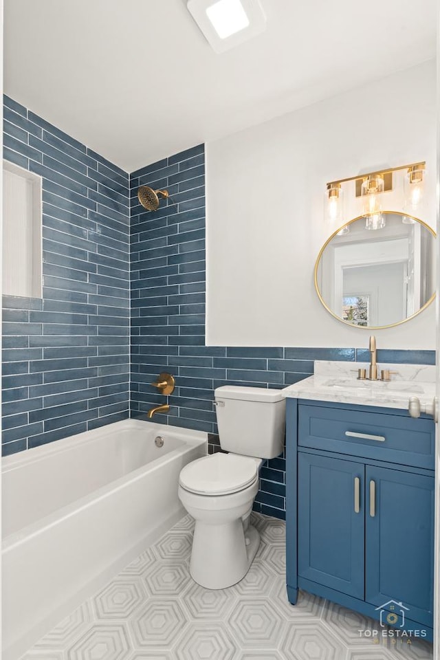 full bathroom featuring vanity, toilet, tile walls, and tiled shower / bath