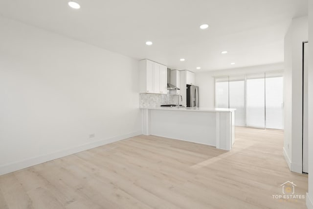 kitchen with tasteful backsplash, light hardwood / wood-style flooring, stainless steel refrigerator with ice dispenser, kitchen peninsula, and white cabinets