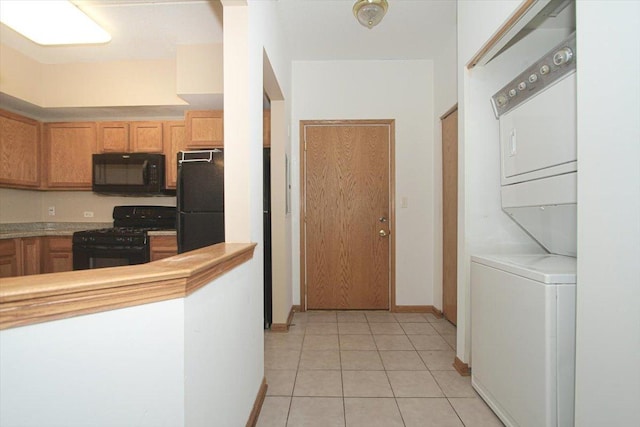 kitchen with black appliances, light tile patterned floors, and stacked washer and dryer