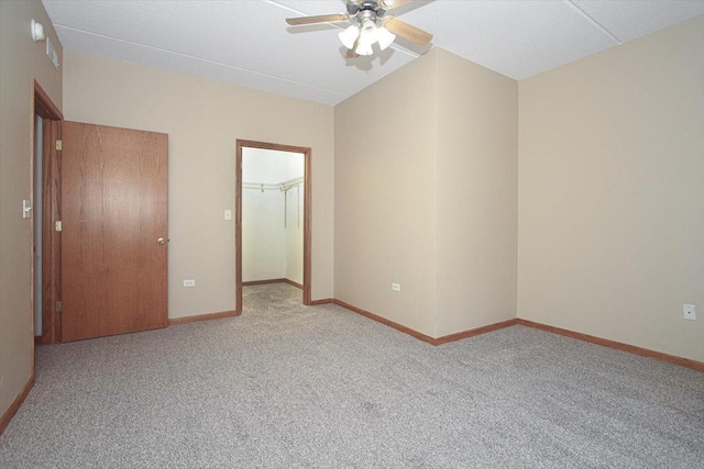 unfurnished bedroom featuring ceiling fan, a closet, a spacious closet, and light carpet