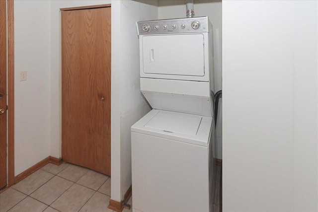 clothes washing area with light tile patterned floors and stacked washer / dryer