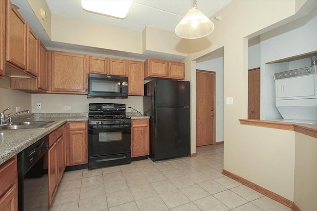 kitchen featuring sink, pendant lighting, light tile patterned flooring, black appliances, and stacked washer and clothes dryer