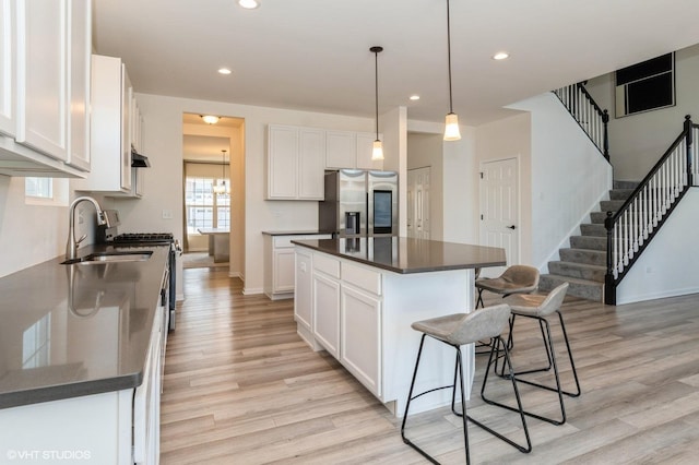 kitchen with sink, a center island, appliances with stainless steel finishes, pendant lighting, and white cabinets