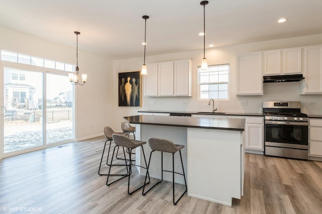 kitchen with white cabinetry, gas stove, light wood-type flooring, and decorative light fixtures