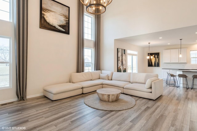 living room featuring an inviting chandelier, light hardwood / wood-style floors, and a healthy amount of sunlight