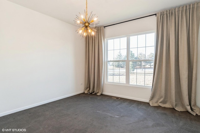 spare room featuring a wealth of natural light, a chandelier, and dark colored carpet