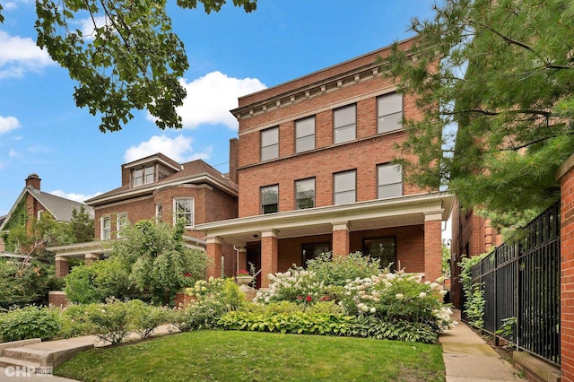 view of front of home featuring brick siding, a front yard, and fence