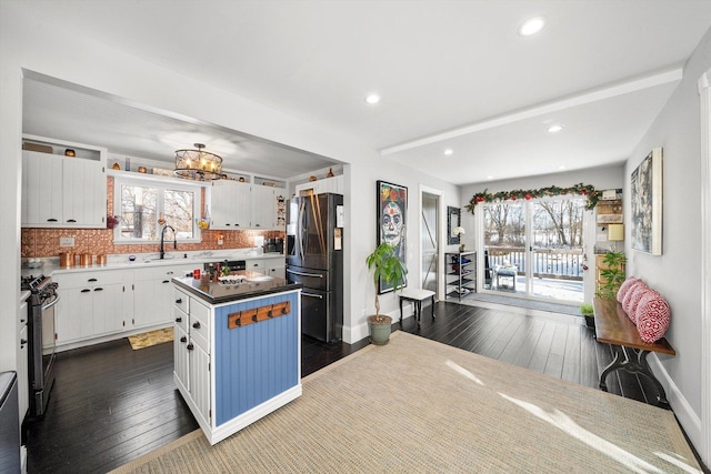 kitchen with stainless steel fridge, a center island, tasteful backsplash, white cabinets, and range with gas cooktop