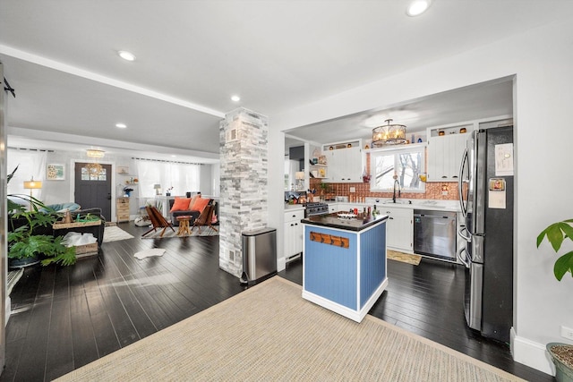 kitchen featuring sink, ornate columns, a center island, stainless steel appliances, and white cabinets