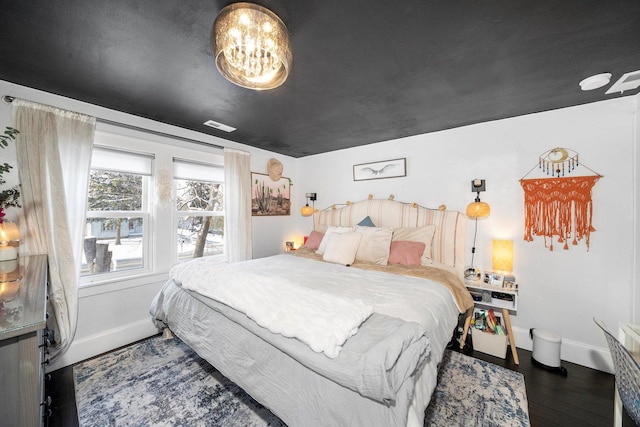 bedroom featuring an inviting chandelier and dark hardwood / wood-style flooring