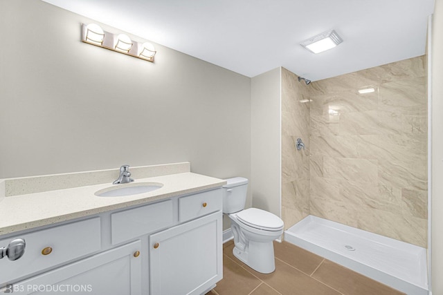 bathroom with vanity, toilet, and a tile shower