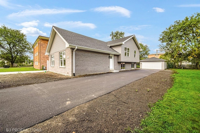 view of front of property featuring a garage, an outdoor structure, and a front lawn