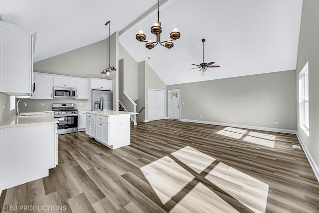 kitchen with appliances with stainless steel finishes, sink, a center island, white cabinetry, and hanging light fixtures