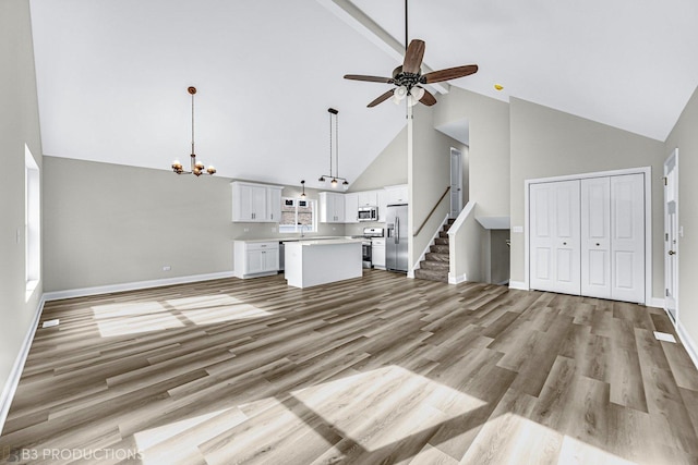 unfurnished living room featuring ceiling fan with notable chandelier, sink, high vaulted ceiling, and light hardwood / wood-style flooring