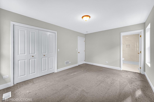 unfurnished bedroom featuring ensuite bath, a closet, and carpet