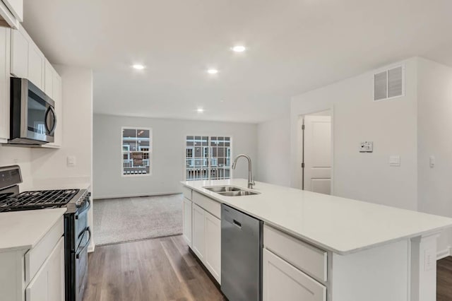 kitchen with a center island with sink, sink, appliances with stainless steel finishes, dark hardwood / wood-style flooring, and white cabinetry