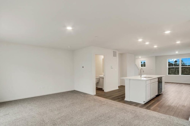 kitchen featuring dark colored carpet, sink, white cabinetry, and an island with sink