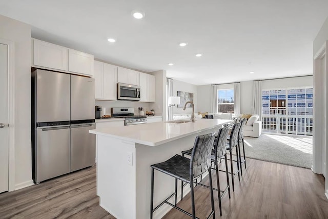 kitchen featuring appliances with stainless steel finishes, sink, a center island with sink, white cabinetry, and a breakfast bar area