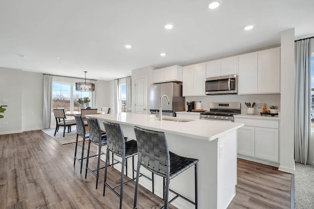 kitchen with white cabinetry, an island with sink, a chandelier, decorative light fixtures, and appliances with stainless steel finishes