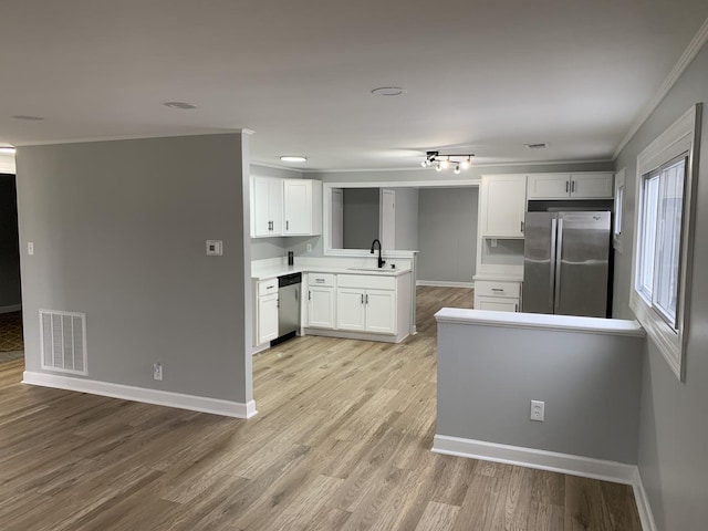 kitchen featuring sink, ornamental molding, white cabinetry, kitchen peninsula, and stainless steel appliances