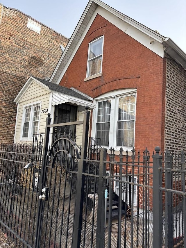 view of front of house with a fenced front yard, brick siding, and a gate