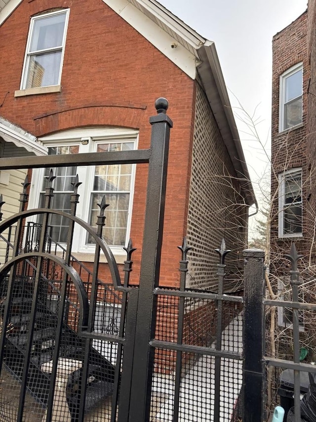 view of side of home with brick siding and fence