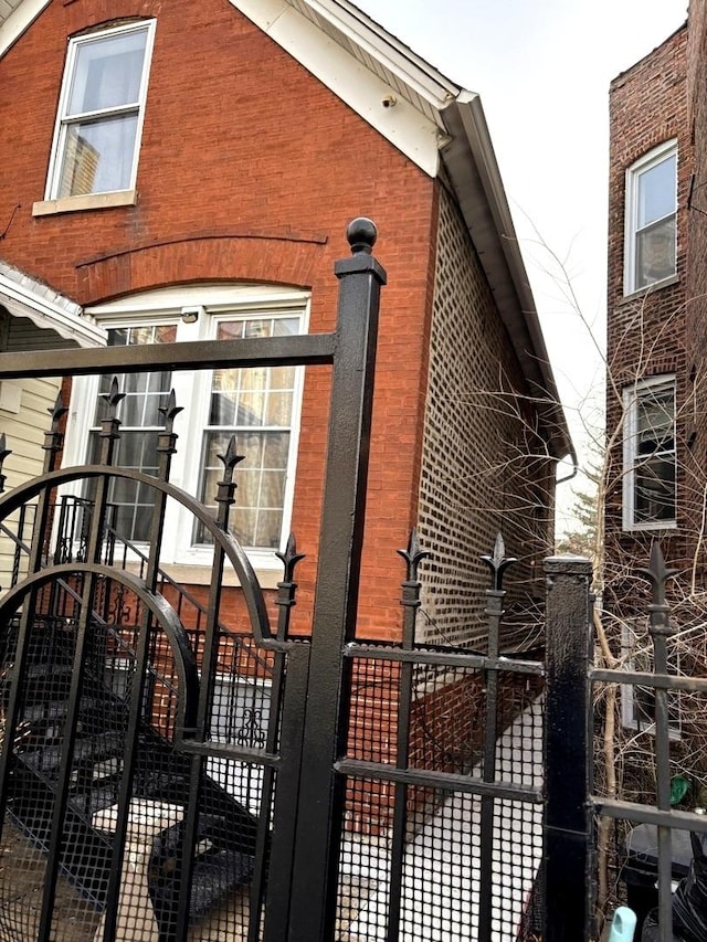 view of property exterior featuring a gate, fence, and brick siding