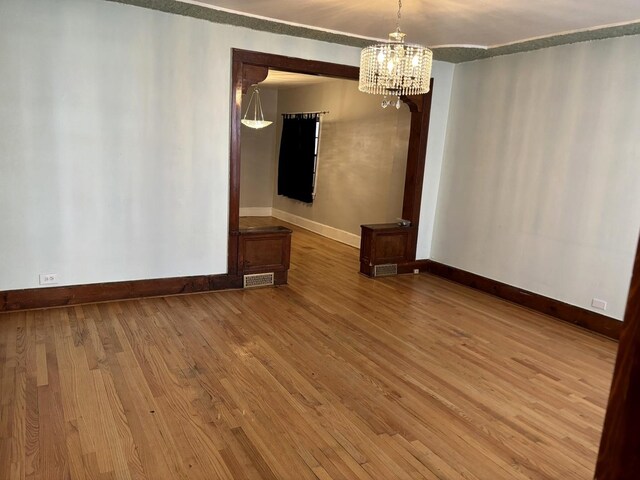 spare room featuring wood-type flooring and an inviting chandelier