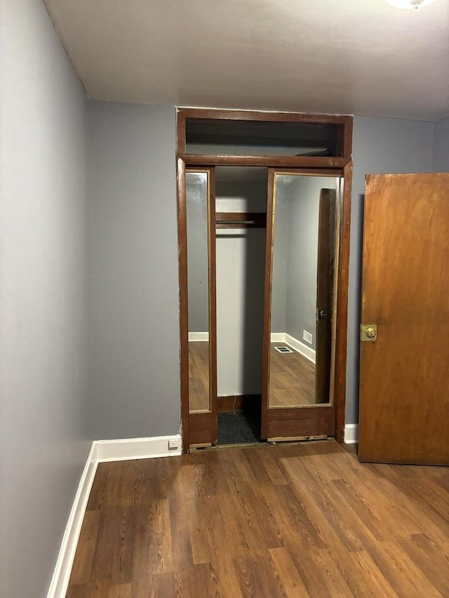 unfurnished bedroom with wood-type flooring and a closet