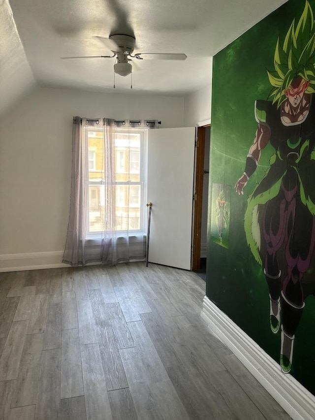 spare room featuring ceiling fan, wood-type flooring, and lofted ceiling