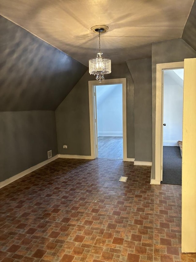 bonus room with vaulted ceiling and a notable chandelier