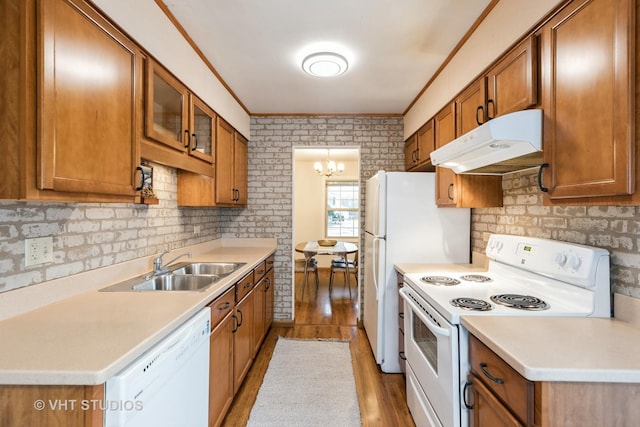 kitchen with white appliances, sink, ornamental molding, light wood-type flooring, and a chandelier