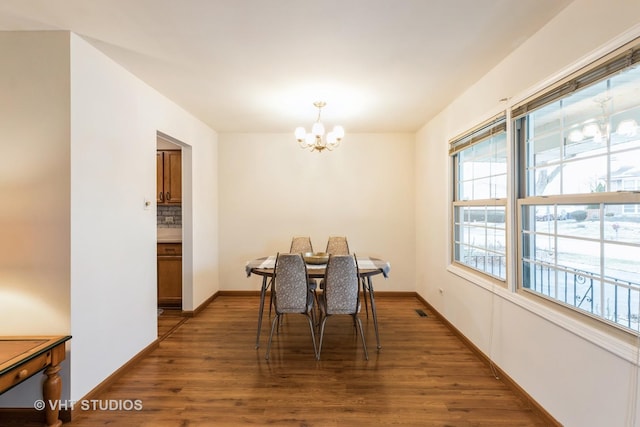 dining space with dark wood-type flooring and a notable chandelier