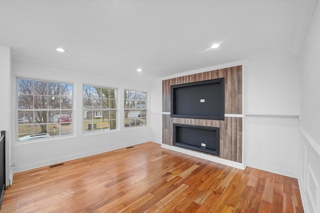 unfurnished living room featuring hardwood / wood-style flooring, a fireplace, and ornamental molding