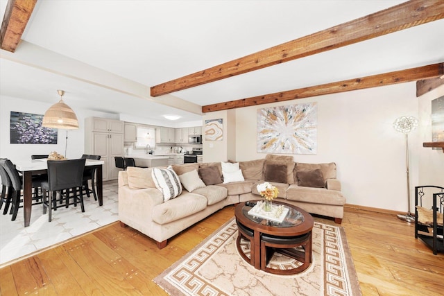 living room with beamed ceiling, light hardwood / wood-style floors, and sink