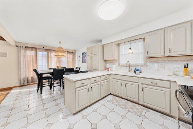 kitchen featuring pendant lighting, sink, electric range, tasteful backsplash, and kitchen peninsula