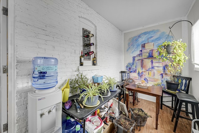 interior space with wood-type flooring, ornamental molding, and brick wall