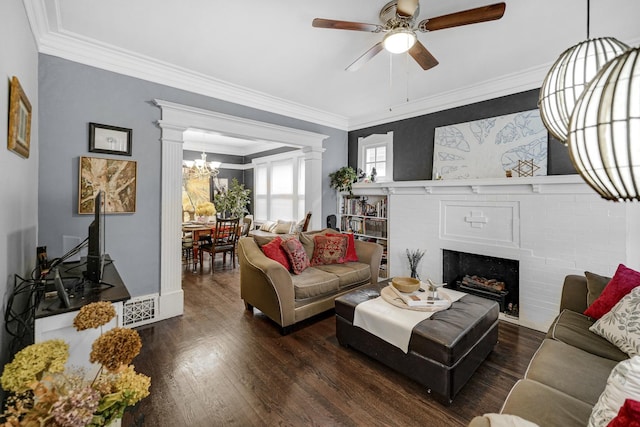 living room featuring hardwood / wood-style floors, ceiling fan with notable chandelier, crown molding, and a brick fireplace