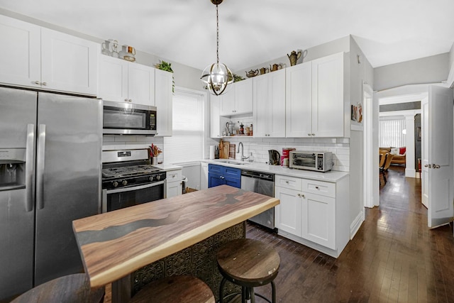 kitchen featuring white cabinetry, sink, pendant lighting, decorative backsplash, and appliances with stainless steel finishes