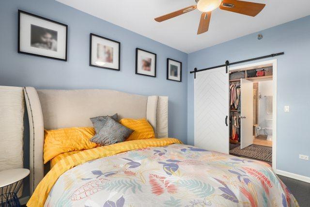 bedroom featuring ceiling fan, a closet, ensuite bath, and a barn door