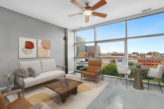 living room featuring light wood-type flooring, expansive windows, and ceiling fan