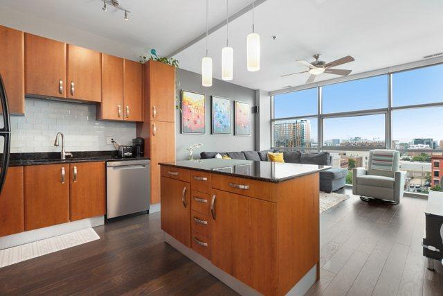 kitchen with dishwasher, sink, a kitchen island, floor to ceiling windows, and dark hardwood / wood-style floors