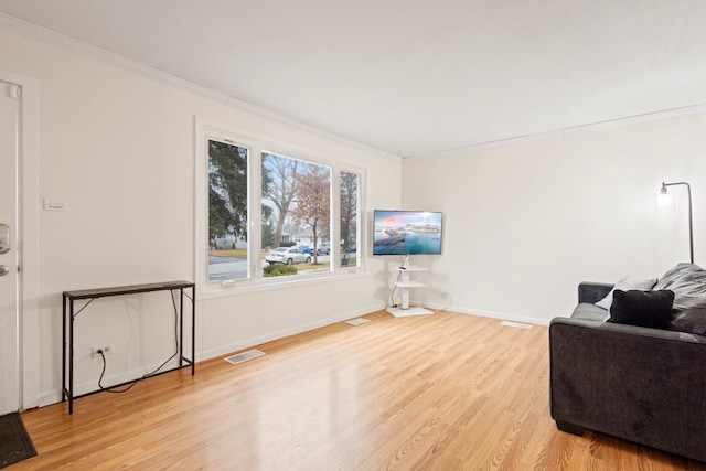 living area with light hardwood / wood-style floors and crown molding