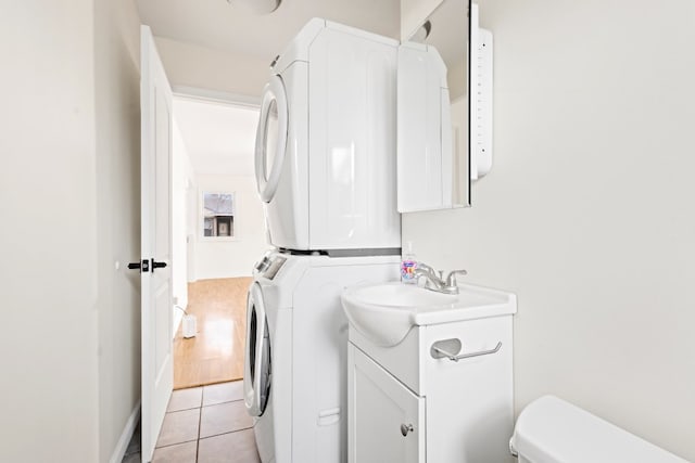 laundry room featuring sink, stacked washer / dryer, and light tile patterned flooring