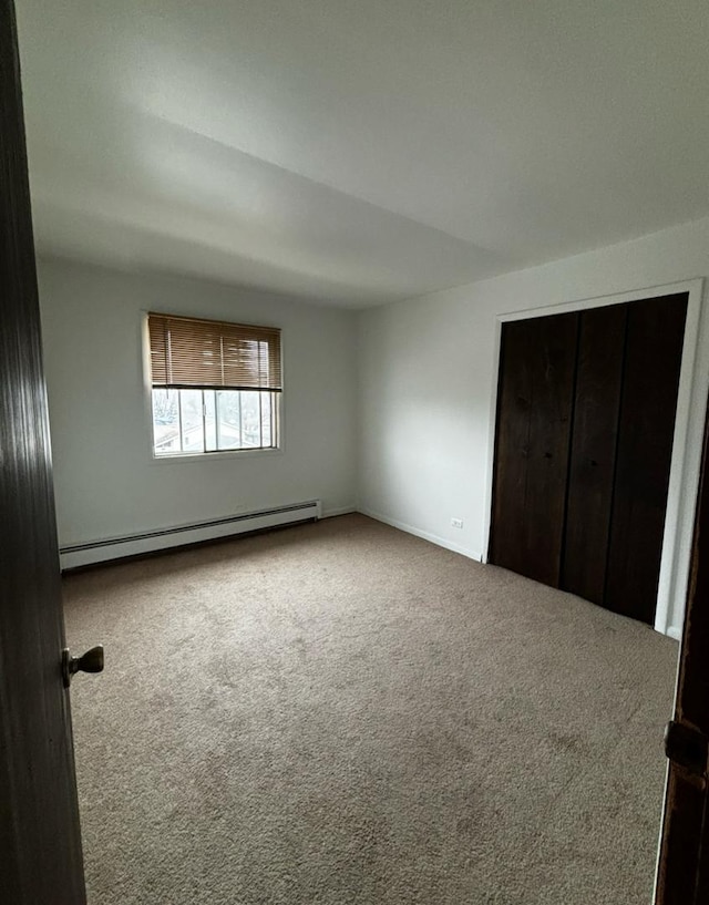 unfurnished bedroom with a baseboard radiator and carpet