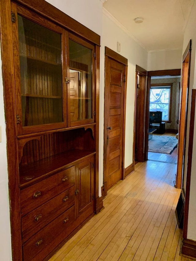 corridor with light hardwood / wood-style floors and ornamental molding