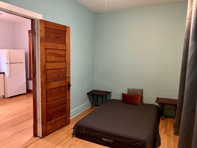 bedroom featuring white refrigerator and light wood-type flooring