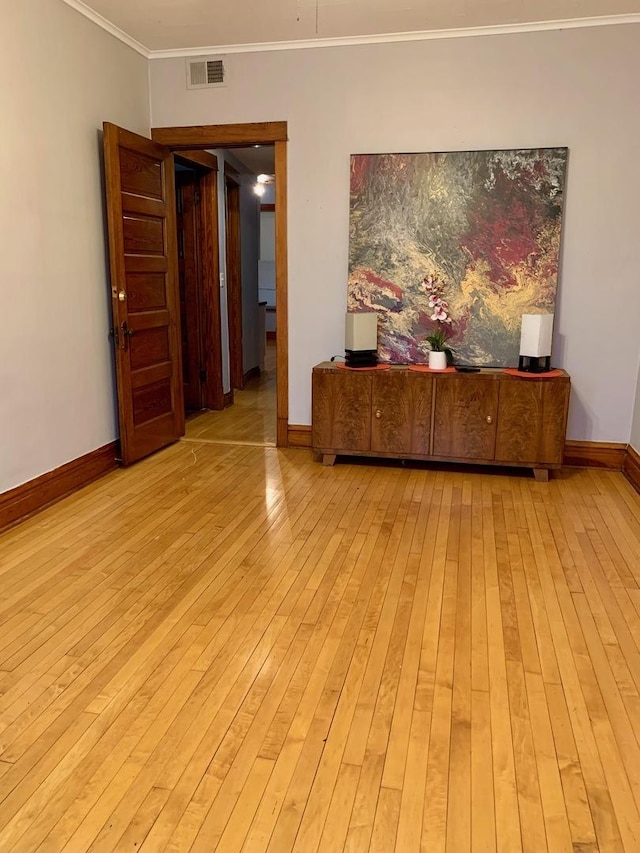 empty room with crown molding and light hardwood / wood-style floors