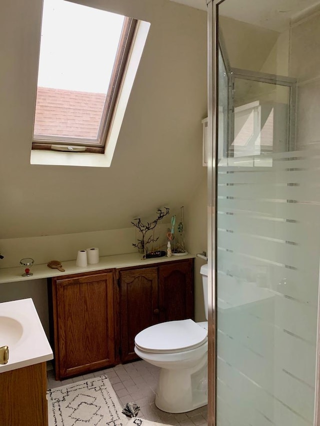 bathroom with a skylight, an enclosed shower, vanity, tile patterned flooring, and toilet